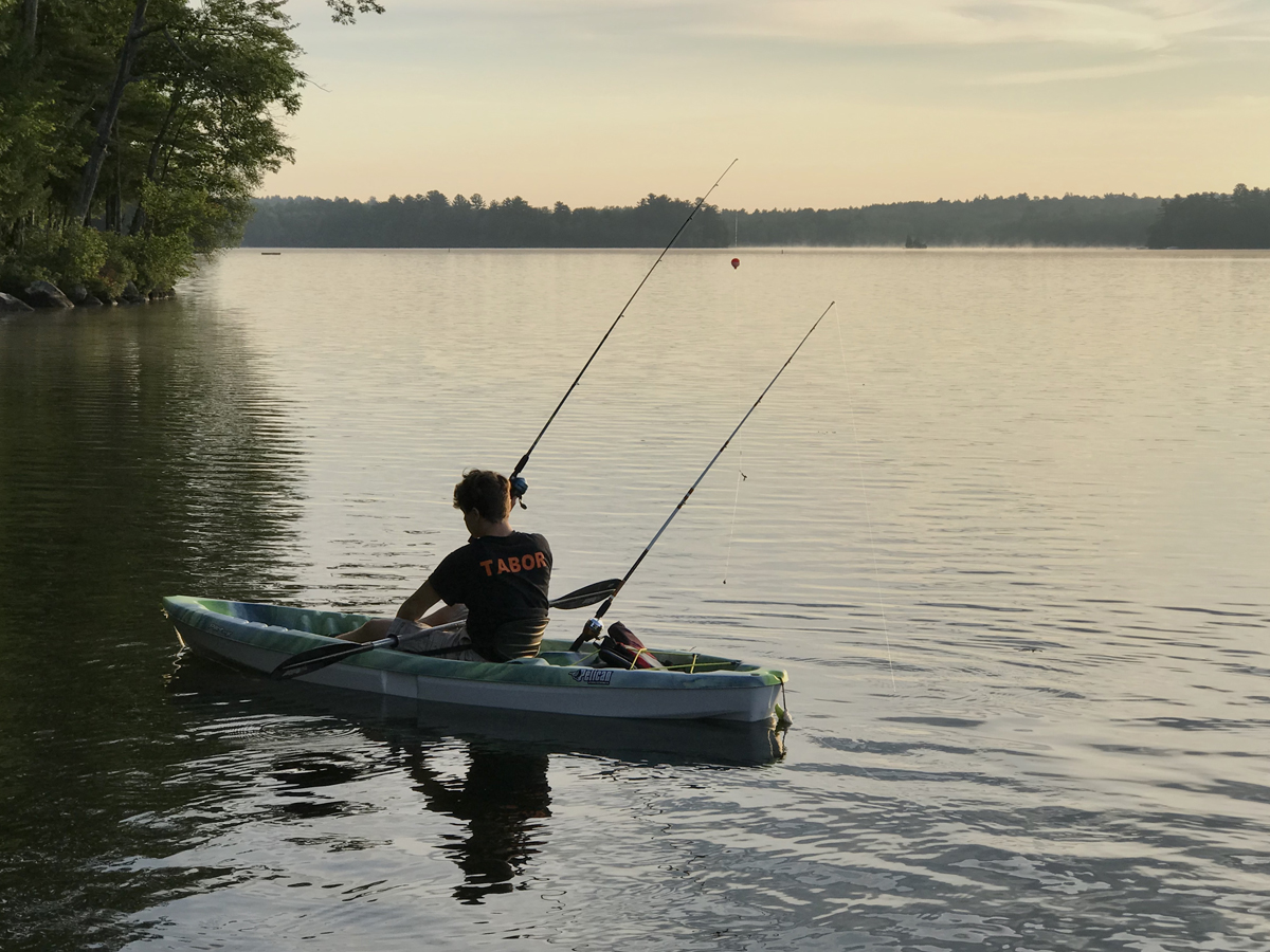 Boy fishing on canoe