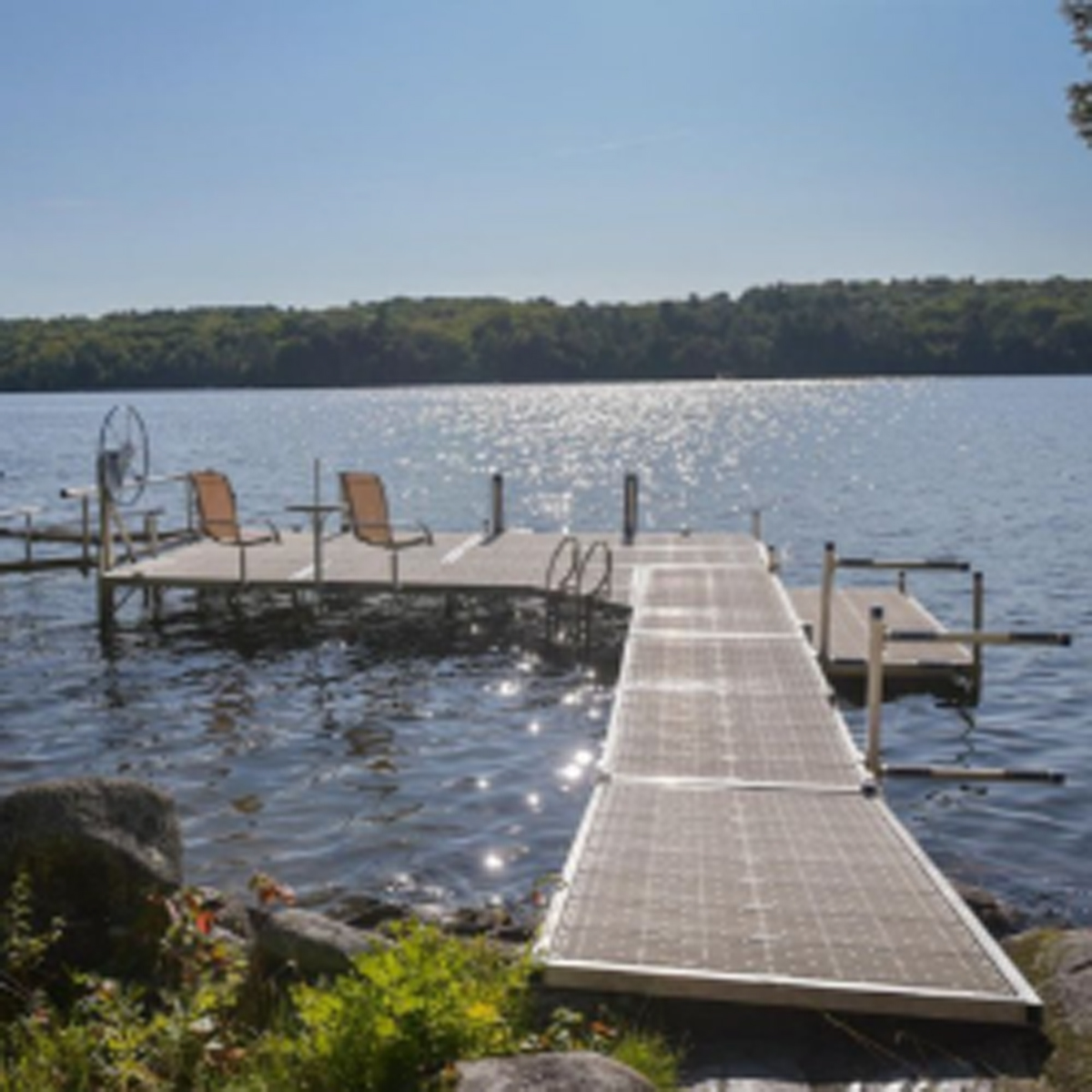 Metal dock with two chairs and bright sun reflecting on the water